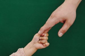 child hand grabbing adult hand