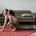 A mother and daughter doing yoga in a living room