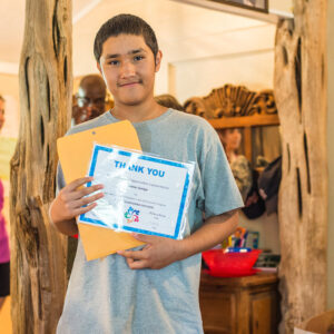 A boy holding a certificate that says thank you
